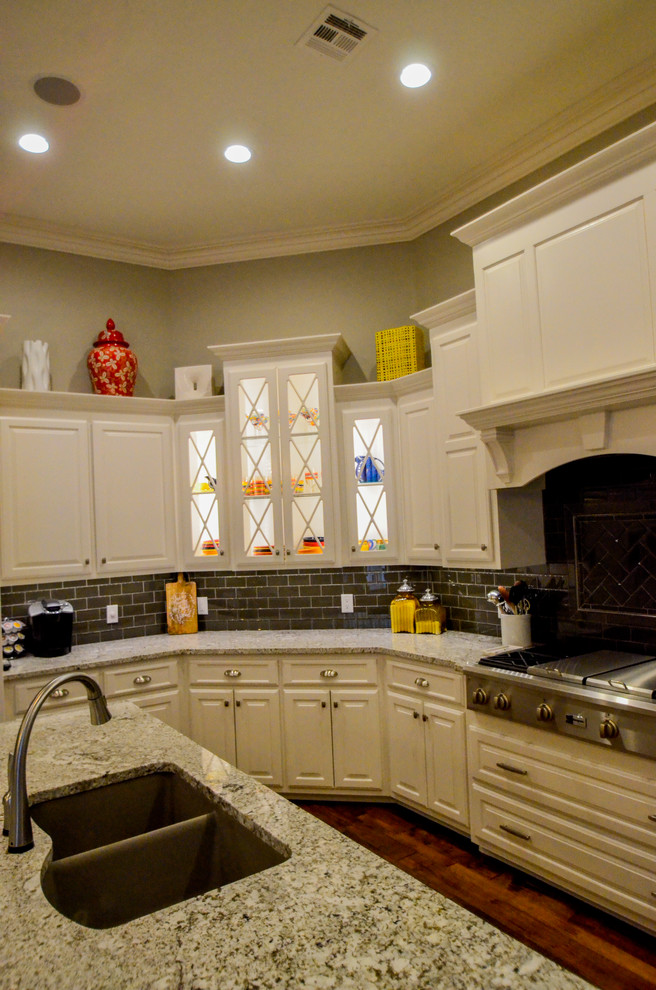 Open concept kitchen - large transitional u-shaped dark wood floor open concept kitchen idea with a double-bowl sink, raised-panel cabinets, white cabinets, granite countertops, gray backsplash, stainless steel appliances and an island