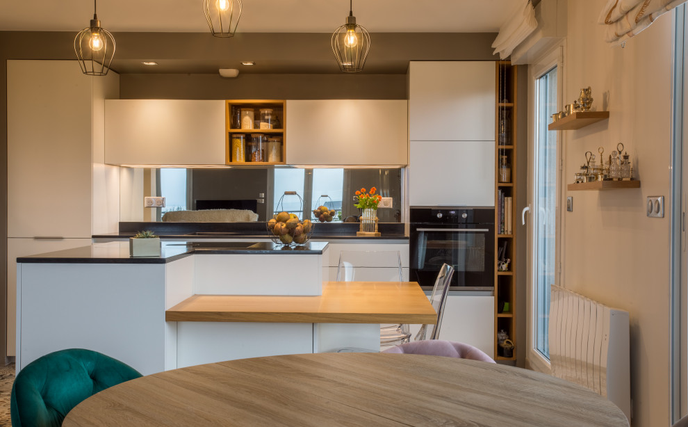 Inspiration for a medium sized modern l-shaped open plan kitchen in Other with an integrated sink, beaded cabinets, white cabinets, granite worktops, mirror splashback, stainless steel appliances, cement flooring, an island, multi-coloured floors and black worktops.