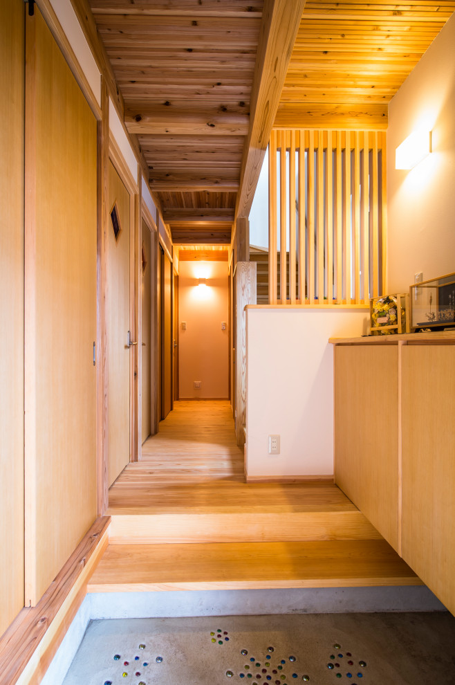 Foto di un ingresso o corridoio stile americano con pareti bianche, pavimento in legno massello medio, una porta singola, una porta in legno bruno e travi a vista