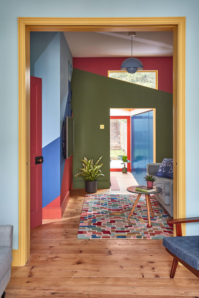 Exempel på ett eklektiskt vardagsrum, med flerfärgade väggar, ljust trägolv och en väggmonterad TV