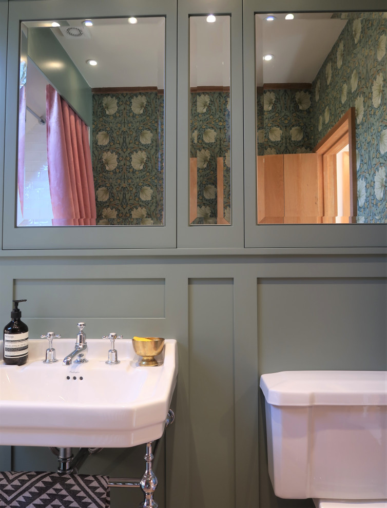 Photo of a mid-sized traditional master bathroom in Sussex with shaker cabinets, green cabinets, a drop-in tub, a shower/bathtub combo, a two-piece toilet, white tile, ceramic tile, green walls, porcelain floors, a console sink, brown floor, a shower curtain, a single vanity, a freestanding vanity, vaulted and panelled walls.