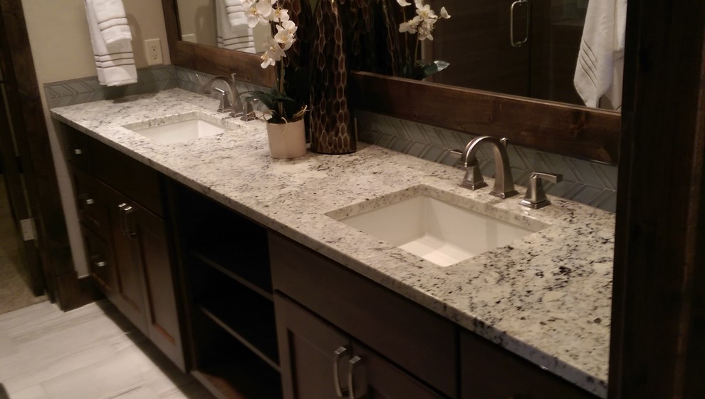This is an example of a mid-sized transitional master bathroom in Denver with shaker cabinets, dark wood cabinets, gray tile, beige walls, porcelain floors, an undermount sink, granite benchtops, glass tile and grey floor.