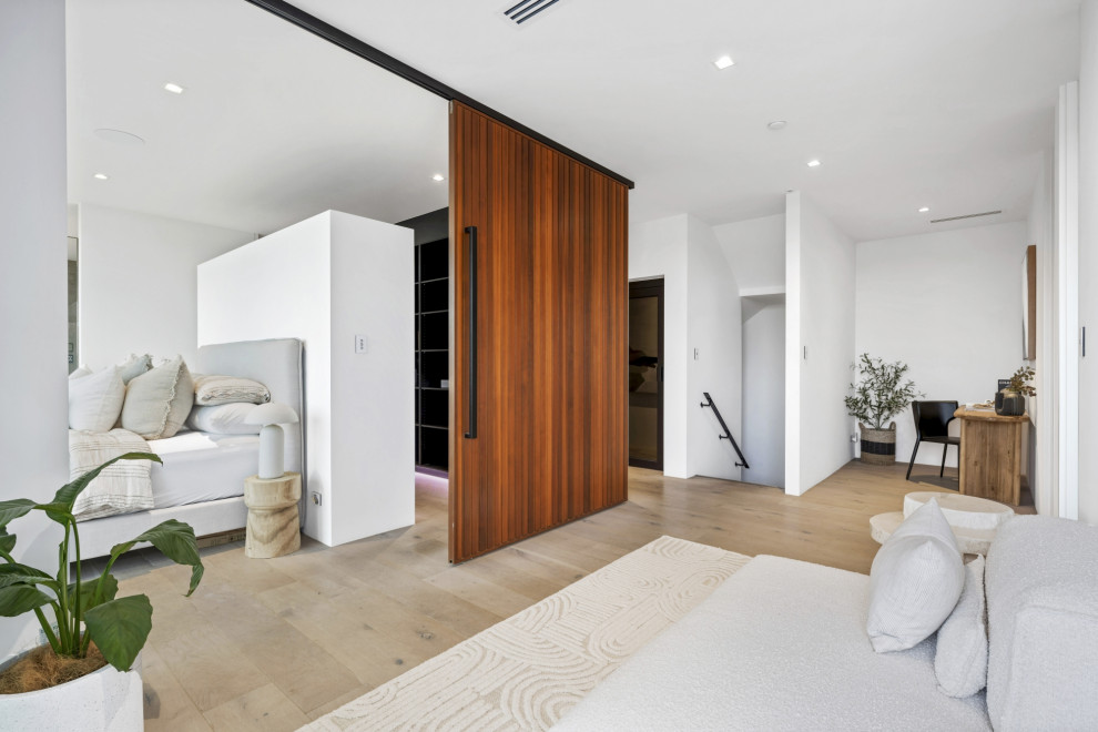 This is an example of a large coastal master bedroom in Adelaide with white walls, light hardwood flooring and beige floors.