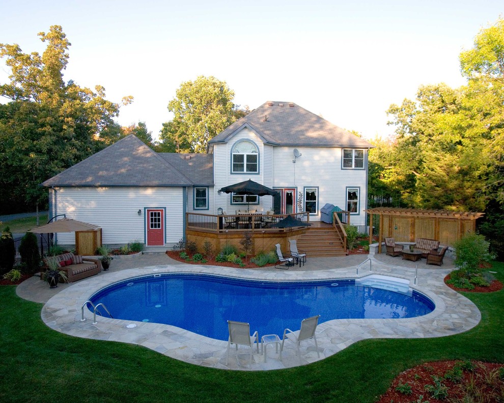 Design ideas for a large traditional backyard custom-shaped pool in New York with natural stone pavers.