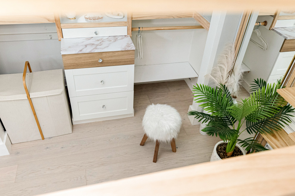 Imagen de armario vestidor abovedado y unisex nórdico pequeño con suelo de madera clara, suelo beige, armarios con rebordes decorativos y puertas de armario de madera clara