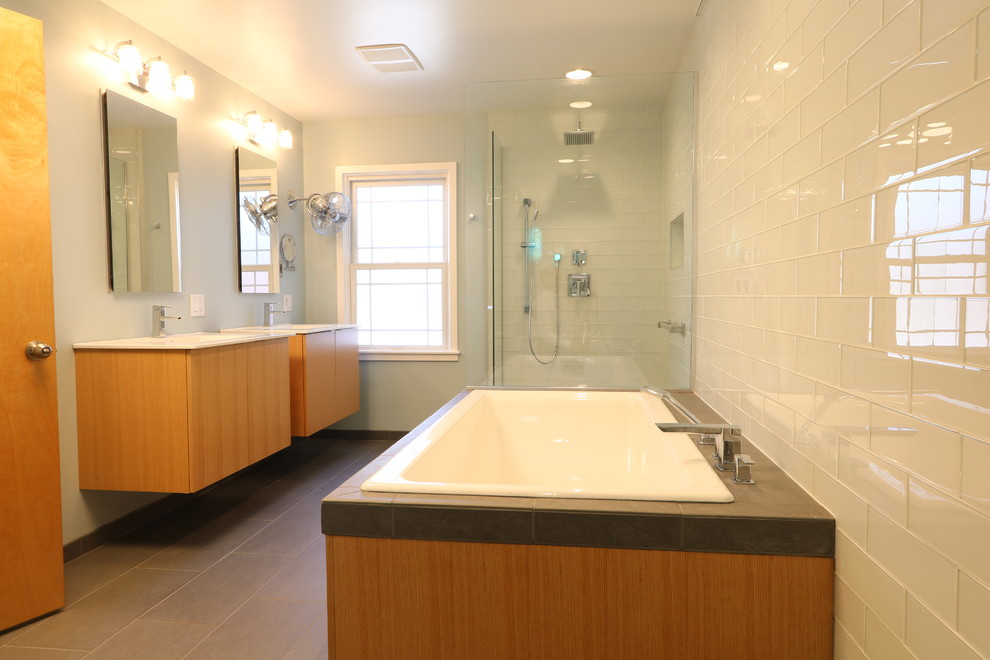 Mid-sized contemporary master bathroom in Other with flat-panel cabinets, medium wood cabinets, a drop-in tub, a curbless shower, a one-piece toilet, white tile, glass tile, blue walls, porcelain floors, an integrated sink and solid surface benchtops.
