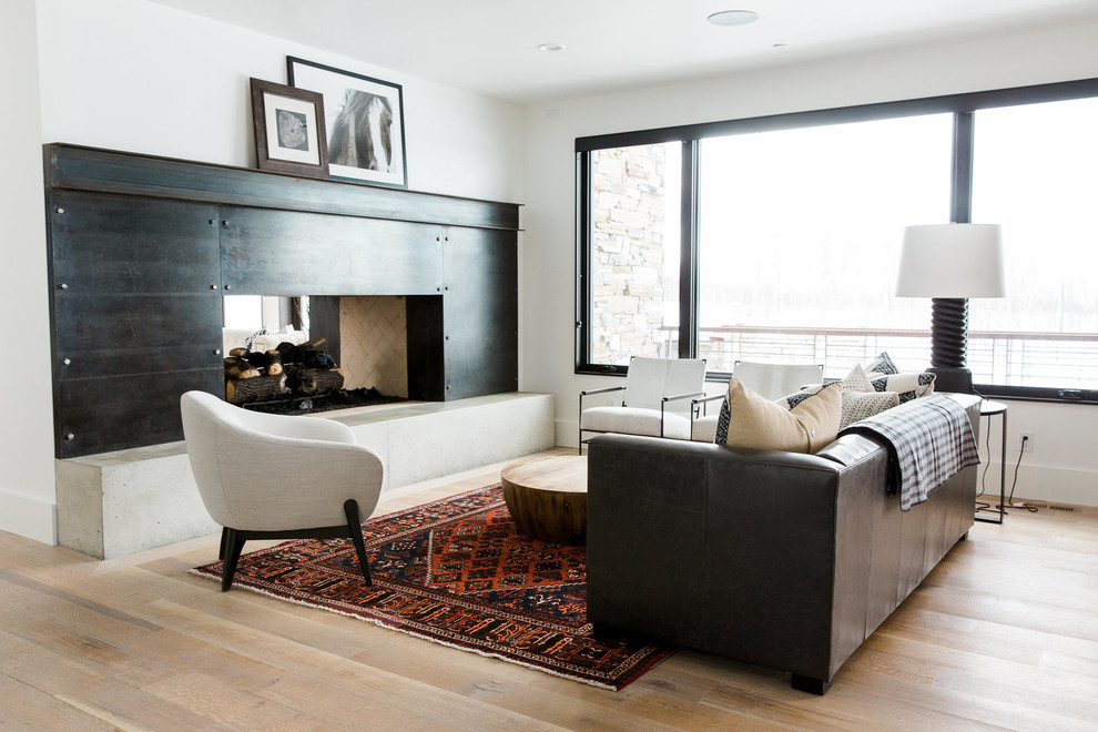 Transitional family room in Salt Lake City with white walls, light hardwood floors, a two-sided fireplace and no tv.