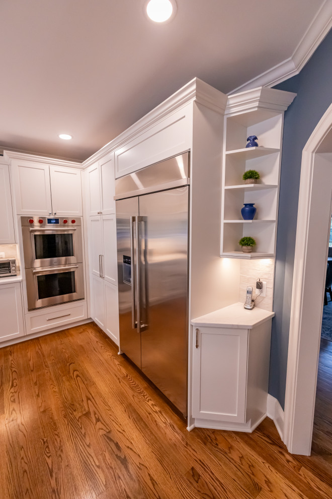 Example of a large transitional u-shaped medium tone wood floor and brown floor eat-in kitchen design in Baltimore with a farmhouse sink, shaker cabinets, blue cabinets, quartz countertops, white backsplash, marble backsplash, stainless steel appliances, an island and white countertops