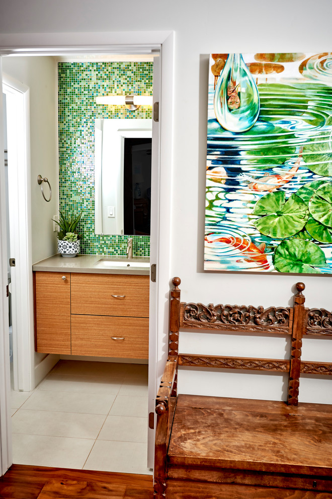 Mid-sized tropical kids bathroom in San Diego with flat-panel cabinets, medium wood cabinets, a corner tub, an alcove shower, a one-piece toilet, green tile, glass tile, white walls, porcelain floors, an undermount sink, engineered quartz benchtops, grey floor, a shower curtain and grey benchtops.