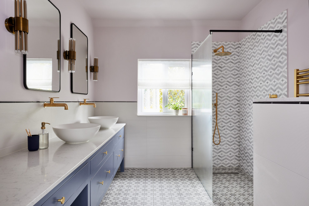 Modernes Duschbad mit flächenbündigen Schrankfronten, blauen Schränken, bodengleicher Dusche, rosa Wandfarbe, Aufsatzwaschbecken, Marmor-Waschbecken/Waschtisch, buntem Boden, offener Dusche, grauer Waschtischplatte, Doppelwaschbecken und eingebautem Waschtisch in Surrey