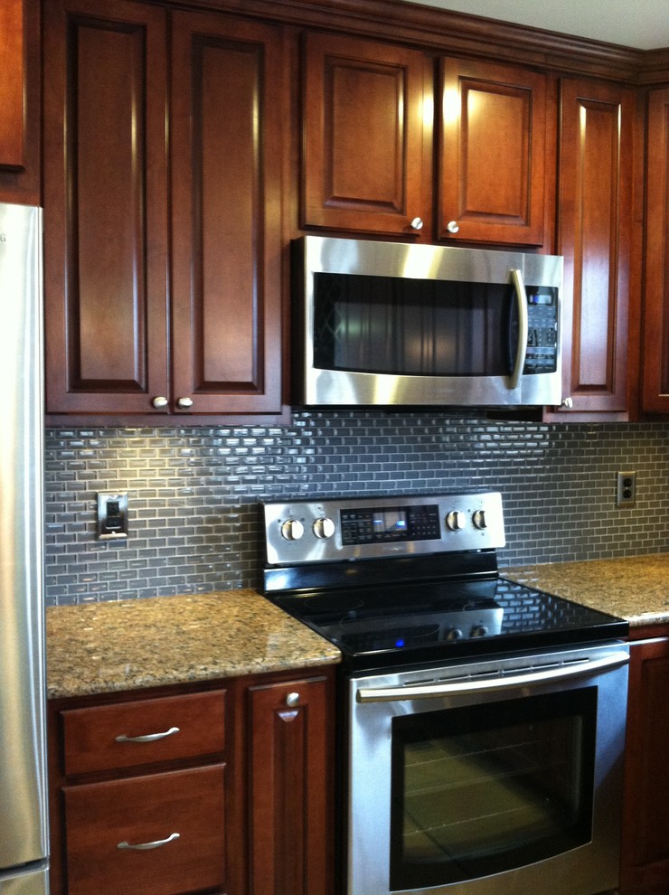 Inspiration for a large transitional u-shaped ceramic tile and beige floor enclosed kitchen remodel with an undermount sink, raised-panel cabinets, dark wood cabinets, granite countertops, blue backsplash, ceramic backsplash, stainless steel appliances and a peninsula