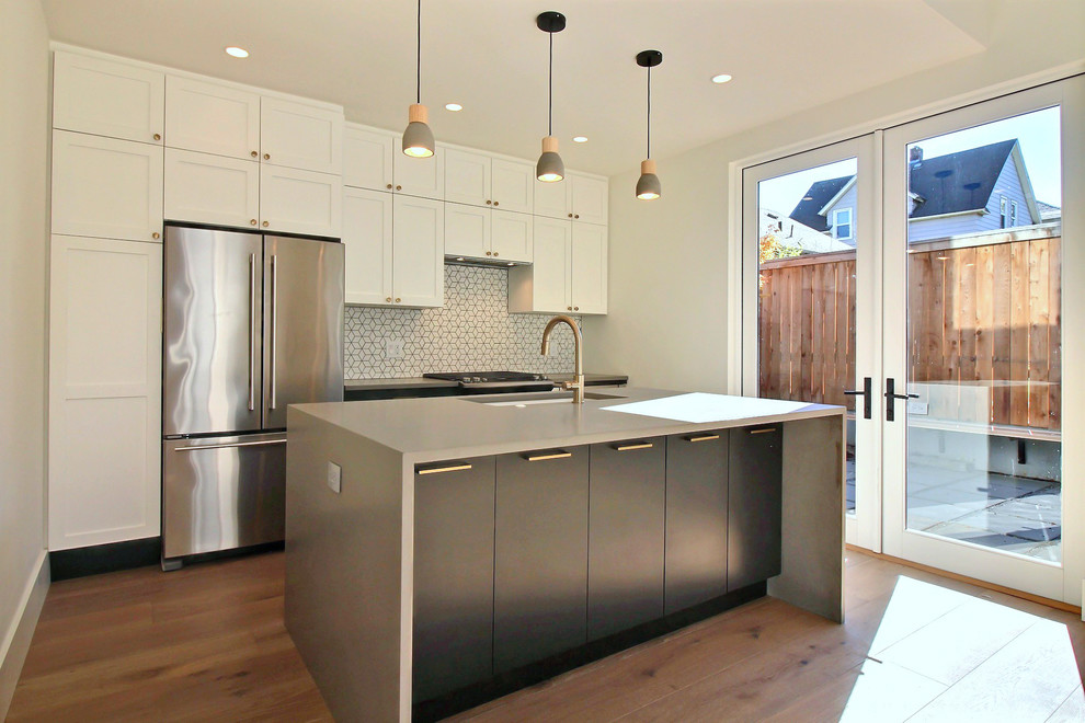 Mid-sized modern u-shaped eat-in kitchen in Portland with an undermount sink, recessed-panel cabinets, white cabinets, quartz benchtops, white splashback, ceramic splashback, stainless steel appliances, light hardwood floors, with island, beige floor and grey benchtop.