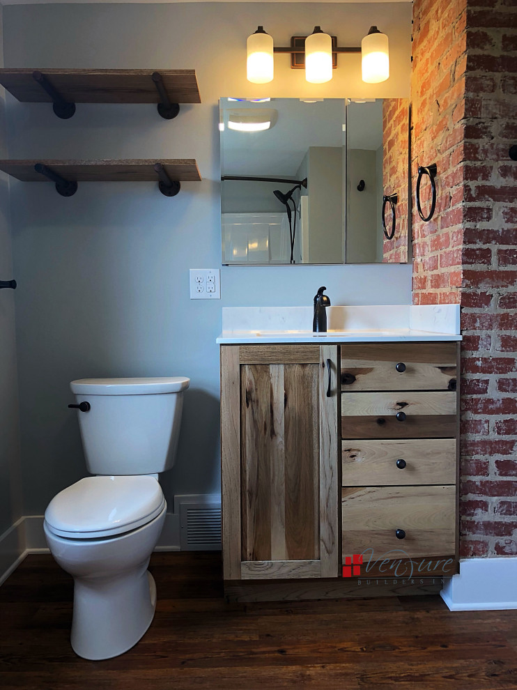 Imagen de cuarto de baño rural pequeño con armarios estilo shaker, puertas de armario de madera oscura, combinación de ducha y bañera, sanitario de dos piezas, paredes azules, suelo vinílico, lavabo integrado, ducha con cortina y encimeras blancas