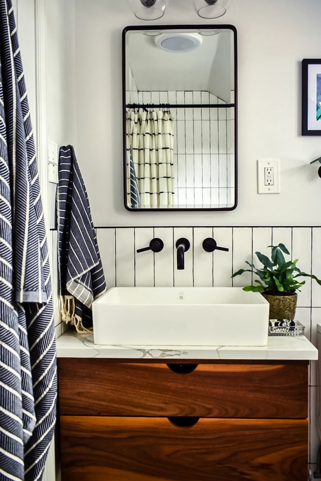 This is an example of a small industrial master bathroom in Philadelphia with flat-panel cabinets, medium wood cabinets, an alcove tub, a shower/bathtub combo, a one-piece toilet, white tile, ceramic tile, white walls, cement tiles, a vessel sink, quartzite benchtops, black floor, a shower curtain, white benchtops, a single vanity and a floating vanity.