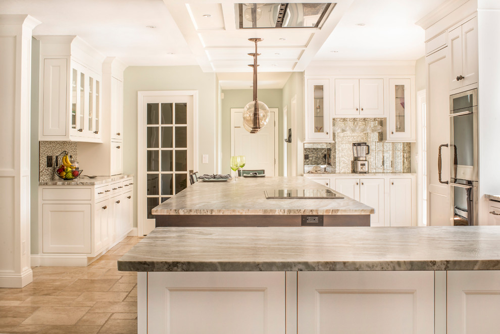 Inspiration for an expansive transitional u-shaped eat-in kitchen in Boston with a farmhouse sink, beaded inset cabinets, white cabinets, granite benchtops, multi-coloured splashback, mosaic tile splashback, panelled appliances, travertine floors, a peninsula, beige floor and brown benchtop.