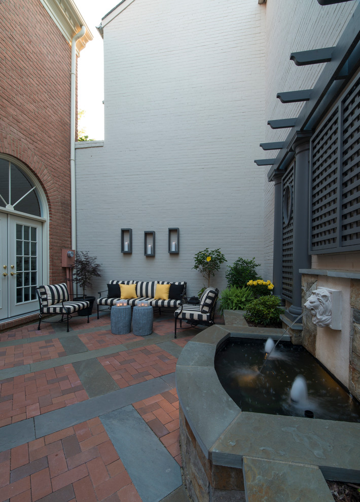 Inspiration for a mid-sized traditional courtyard patio in DC Metro with a water feature and no cover.