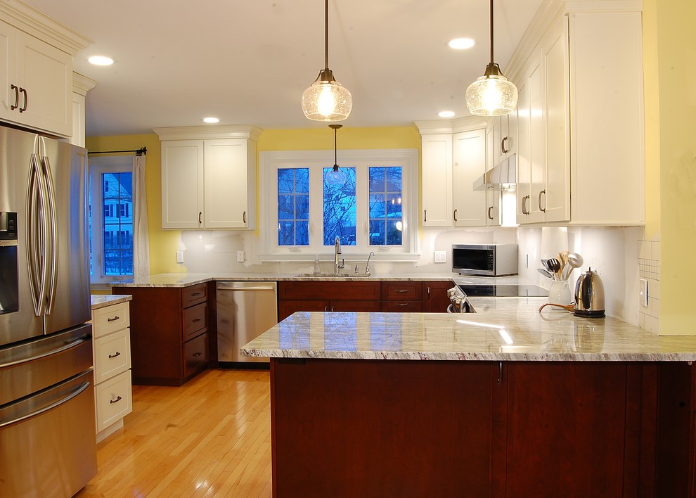 Example of a mid-sized transitional u-shaped light wood floor eat-in kitchen design in Boston with an undermount sink, shaker cabinets, white cabinets, quartz countertops, stainless steel appliances and a peninsula