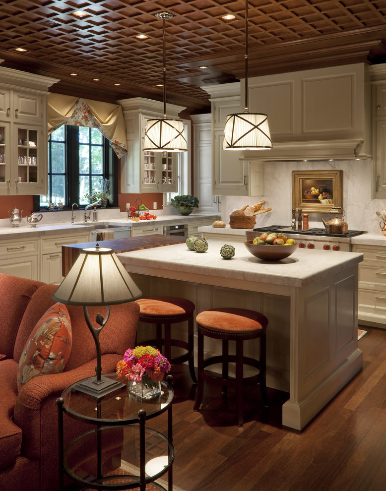Inspiration for a mid-sized traditional open plan kitchen in Milwaukee with glass-front cabinets, stainless steel appliances, medium hardwood floors, brown floor, a farmhouse sink, white cabinets, marble benchtops, white splashback, stone slab splashback and with island.