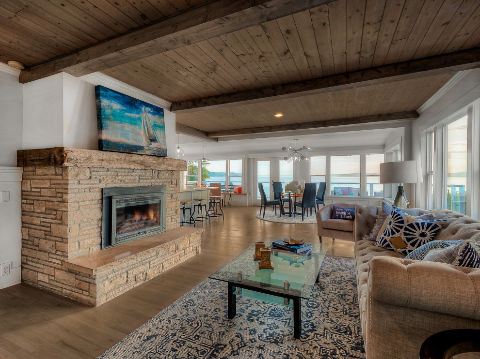 Photo of a beach style open concept living room in Seattle with white walls, medium hardwood floors, a standard fireplace, brown floor and wood.