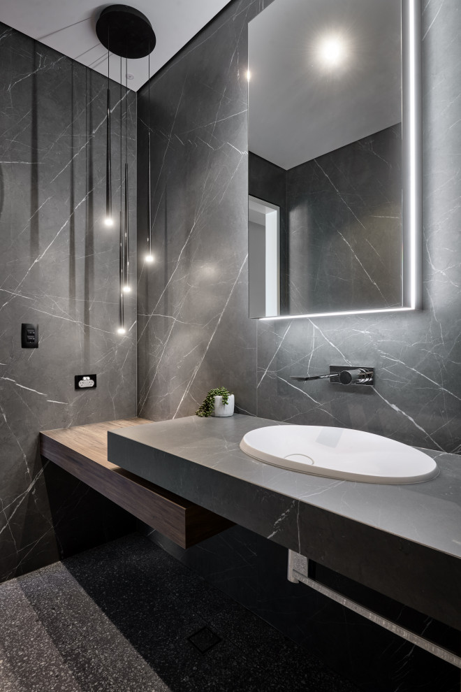 Design ideas for a large contemporary powder room in Perth with open cabinets, medium wood cabinets, a wall-mount toilet, black and white tile, pebble tile, terrazzo floors, a drop-in sink, engineered quartz benchtops, black floor, grey benchtops and a floating vanity.