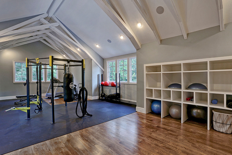 Photo of a large country home weight room in Houston with grey walls, medium hardwood floors and brown floor.