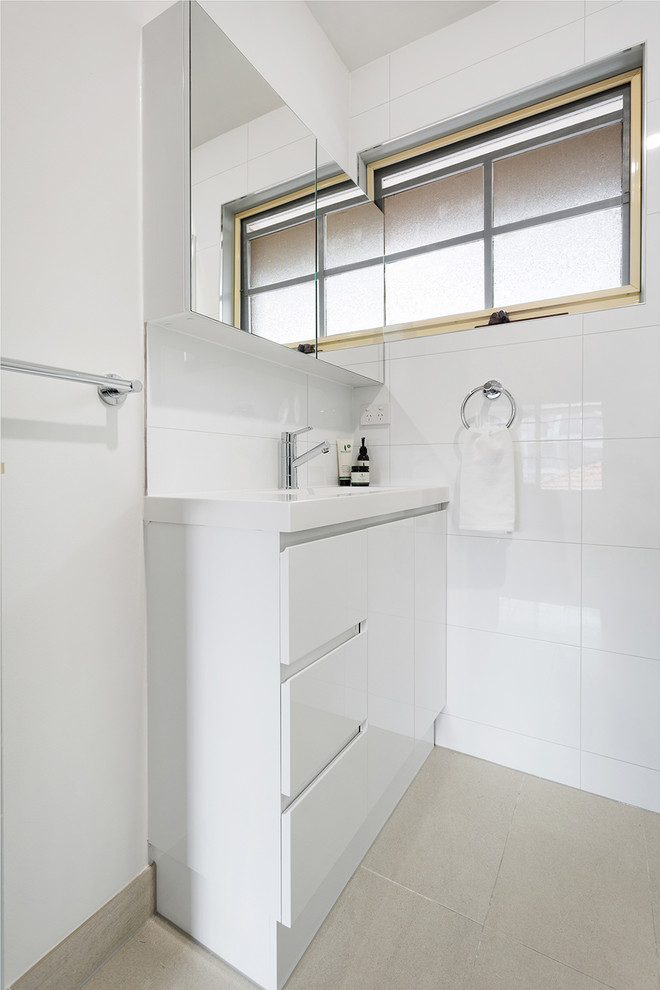 Design ideas for a small contemporary bathroom in Melbourne with flat-panel cabinets, white cabinets, a corner shower, a one-piece toilet, white tile, porcelain tile, white walls, porcelain floors, an integrated sink, beige floor, a hinged shower door and white benchtops.