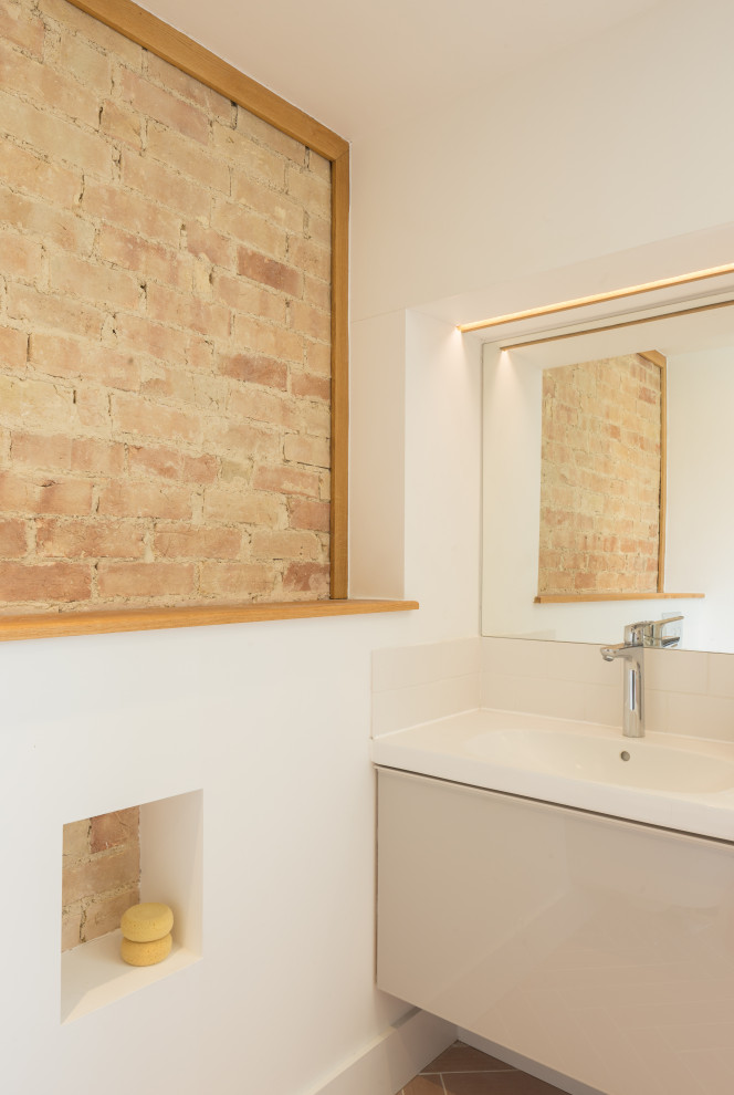 Mid-sized contemporary kids bathroom in Cambridgeshire with flat-panel cabinets, beige cabinets, pink tile, porcelain floors, a single vanity, a floating vanity and brick walls.