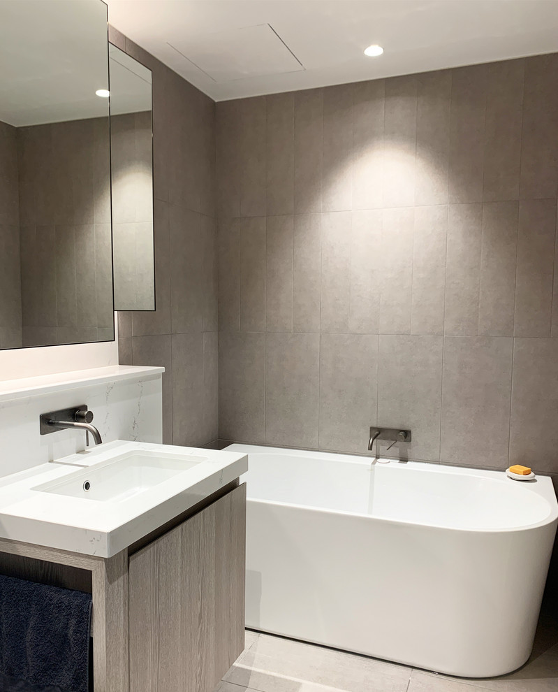 This is an example of a small modern master bathroom in Melbourne with shaker cabinets, light wood cabinets, a freestanding tub, an open shower, a wall-mount toilet, gray tile, cement tile, grey walls, cement tiles, a drop-in sink, grey floor, an open shower and white benchtops.