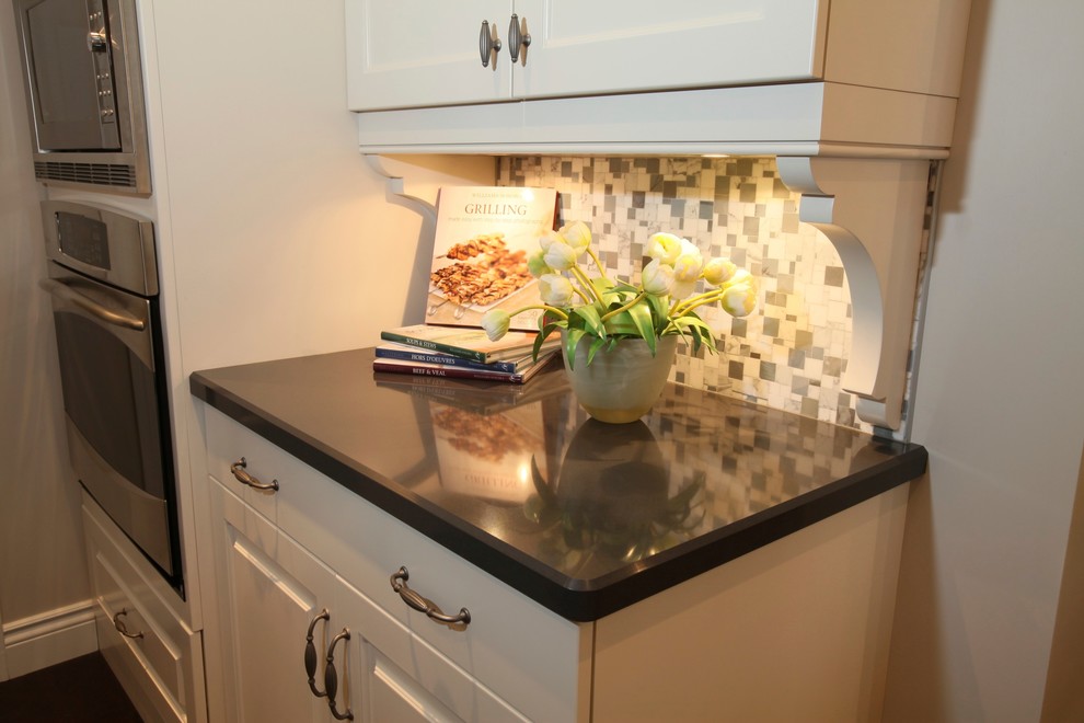 Inspiration for a mid-sized transitional l-shaped medium tone wood floor eat-in kitchen remodel with an undermount sink, raised-panel cabinets, white cabinets, quartz countertops, multicolored backsplash, mosaic tile backsplash, stainless steel appliances and an island