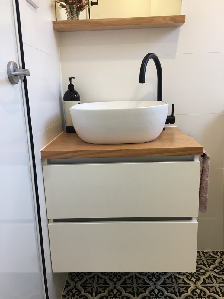 Photo of a small modern 3/4 bathroom in Sydney with flat-panel cabinets, white cabinets, a corner shower, a one-piece toilet, white tile, ceramic tile, white walls, ceramic floors, a vessel sink, wood benchtops, multi-coloured floor and an open shower.