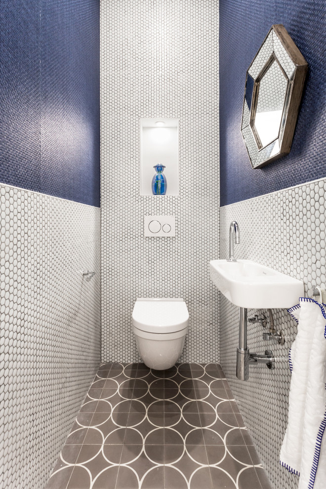 Photo of a small contemporary powder room in Barcelona with white walls, open cabinets, a wall-mount toilet, blue tile, white tile, mosaic tile, a wall-mount sink and brown floor.