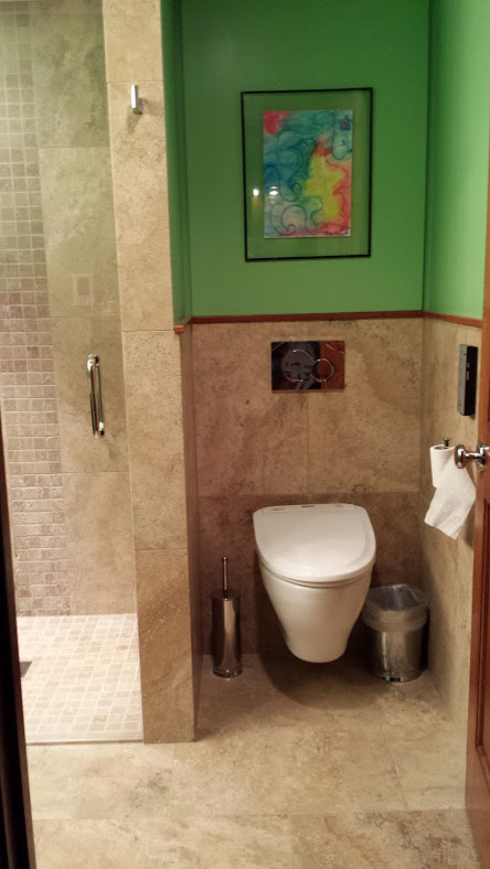 Small eclectic 3/4 beige tile and stone tile travertine floor home design photo with an undermount sink, brown cabinets, limestone countertops, a wall-mount toilet and green walls