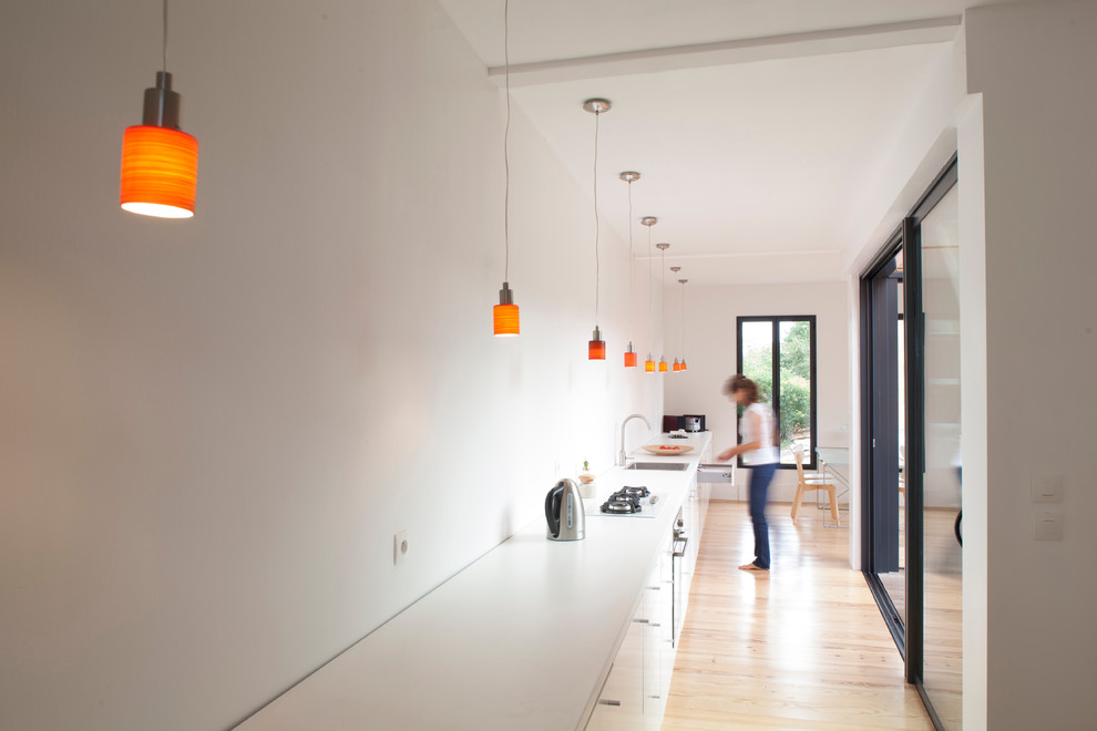 This is an example of a large contemporary single-wall eat-in kitchen in Bordeaux with a drop-in sink, flat-panel cabinets, white cabinets, light hardwood floors and no island.