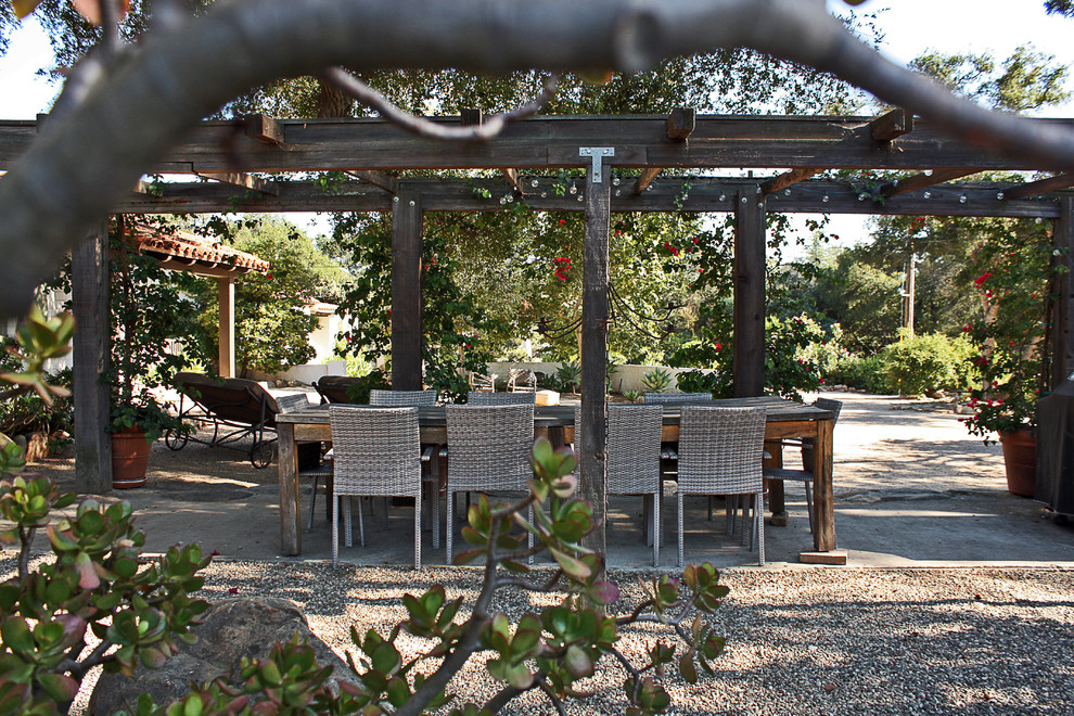 Mediterranean patio in Santa Barbara with gravel and a pergola.