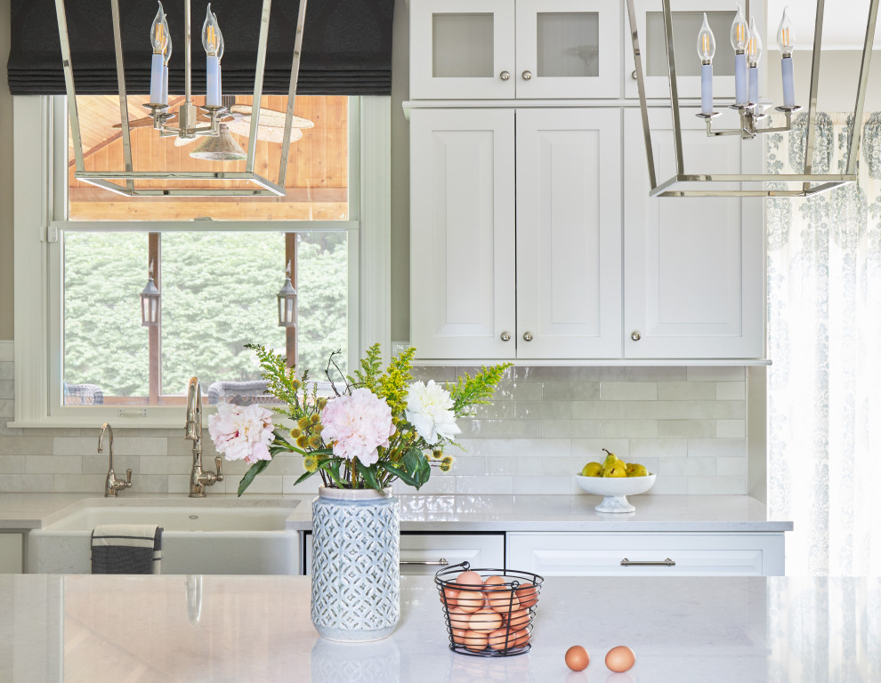 Eat-in kitchen - mid-sized transitional galley medium tone wood floor, brown floor and tray ceiling eat-in kitchen idea in Chicago with a farmhouse sink, shaker cabinets, white cabinets, quartzite countertops, white backsplash, subway tile backsplash, white appliances, an island and white countertops