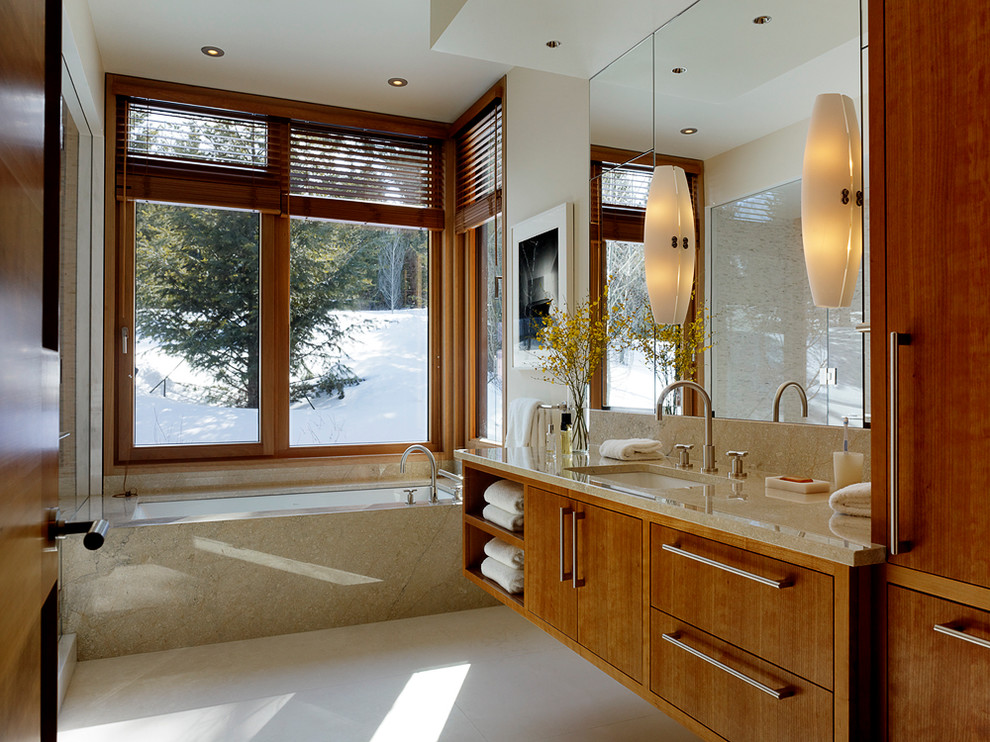 This is an example of a contemporary bathroom in Other with an undermount sink, flat-panel cabinets, medium wood cabinets, an alcove tub, beige tile and beige benchtops.