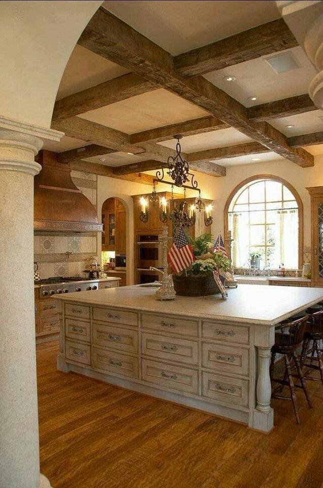 Large mountain style u-shaped medium tone wood floor and brown floor enclosed kitchen photo in Orange County with a farmhouse sink, recessed-panel cabinets, beige cabinets, solid surface countertops, beige backsplash, stainless steel appliances and an island