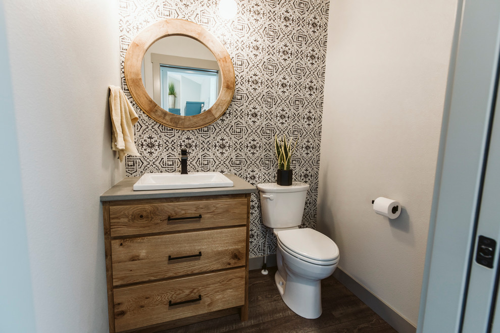 This is an example of a mid-sized country bathroom in Other with flat-panel cabinets, light wood cabinets, a two-piece toilet, white walls, vinyl floors, a drop-in sink, engineered quartz benchtops, brown floor and grey benchtops.