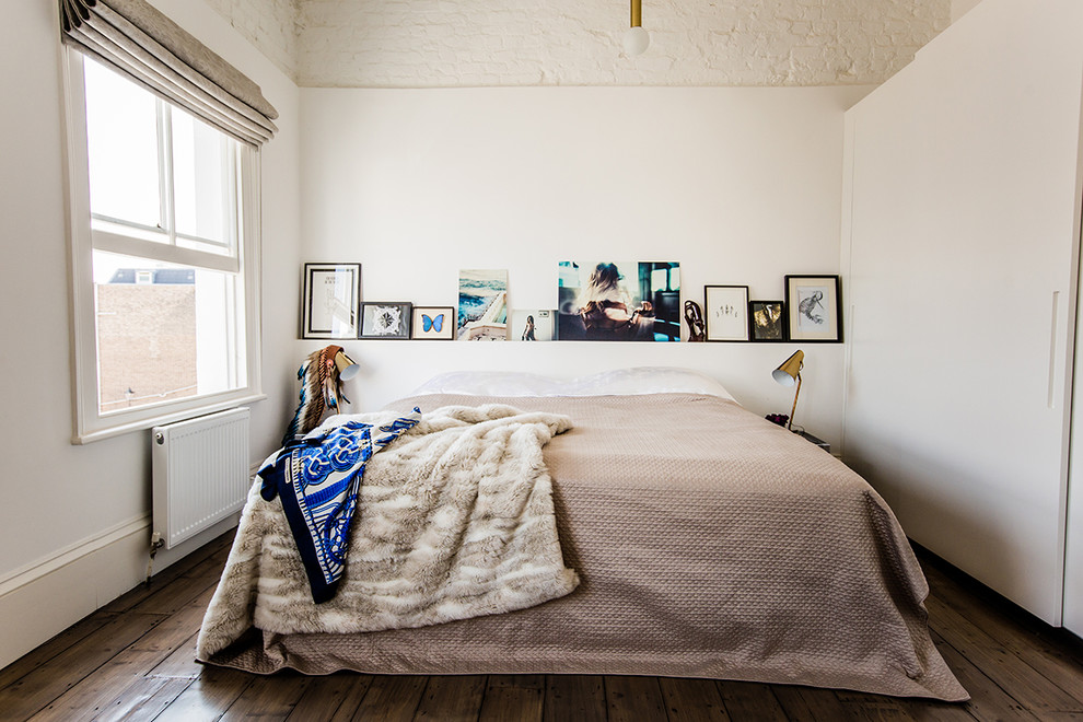 Photo of an eclectic bedroom in London with white walls and medium hardwood floors.