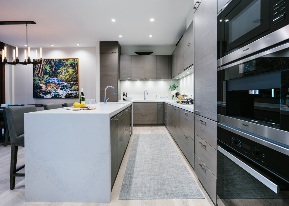 Large contemporary l-shaped eat-in kitchen in Vancouver with an undermount sink, flat-panel cabinets, dark wood cabinets, quartzite benchtops, white splashback, stone slab splashback, panelled appliances, medium hardwood floors, with island and grey floor.