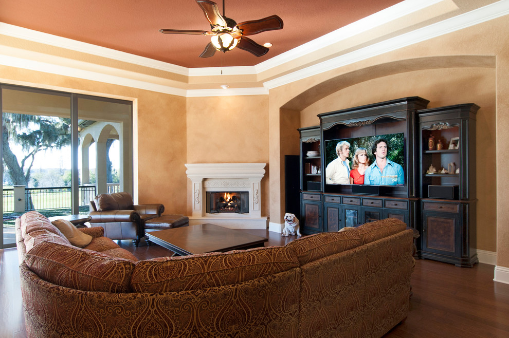 Photo of a large mediterranean open concept family room in Tampa with orange walls, dark hardwood floors, a standard fireplace, a stone fireplace surround and a built-in media wall.
