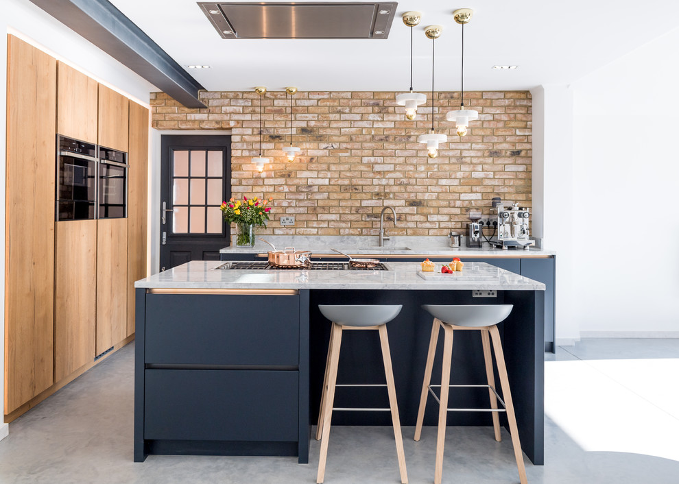 This is an example of a large industrial u-shaped kitchen in London with with island, flat-panel cabinets, blue cabinets, brick splashback, grey floor and grey benchtop.