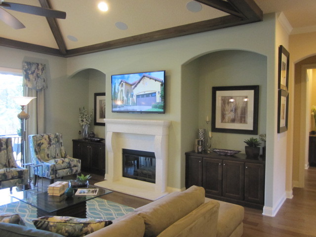 Photo of a mid-sized mediterranean open concept family room in Jacksonville with blue walls, medium hardwood floors, a standard fireplace and a wood fireplace surround.