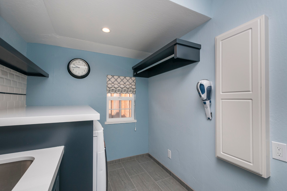 Photo of a mid-sized transitional single-wall utility room in San Francisco with an undermount sink, recessed-panel cabinets, black cabinets, quartz benchtops, blue walls, porcelain floors and a side-by-side washer and dryer.