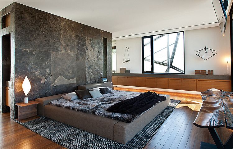 Large contemporary bedroom in New York with white walls, dark hardwood floors and no fireplace.