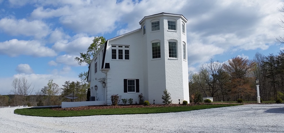 This is an example of a mid-sized country two-storey brick white exterior in Other with a gambrel roof.