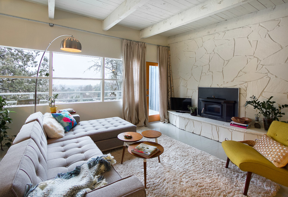 Inspiration for a mid-sized midcentury open concept living room in Boise with a stone fireplace surround, beige walls, painted wood floors, a wood stove and a freestanding tv.
