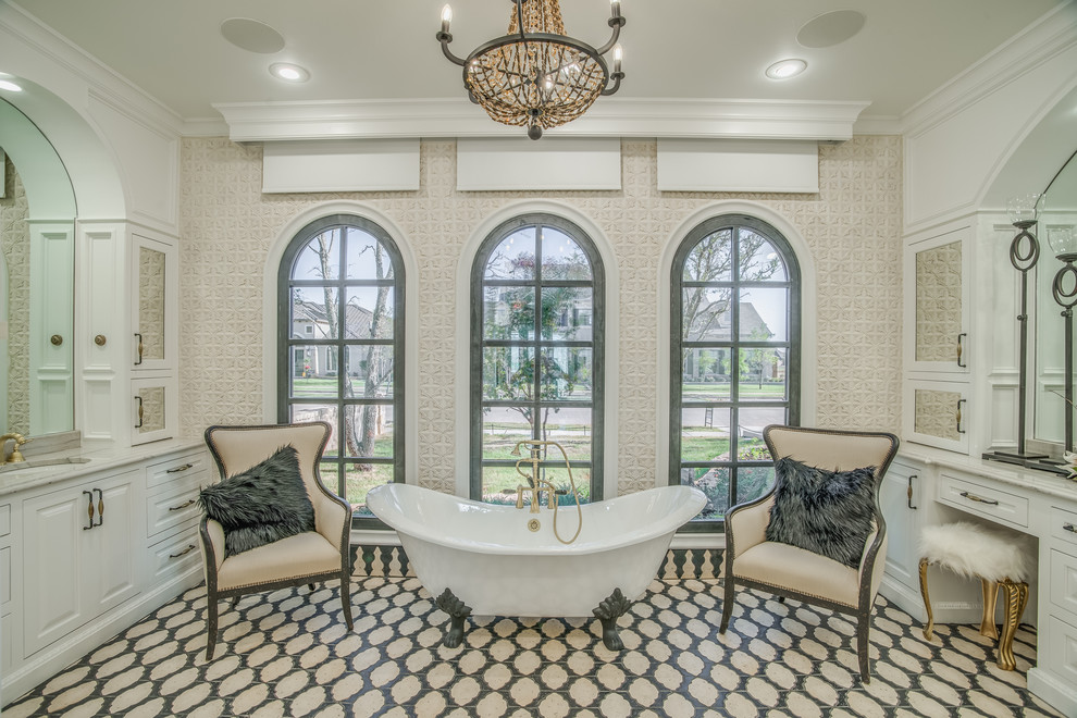 This is an example of a large traditional master bathroom in Austin with raised-panel cabinets, white cabinets, a claw-foot tub, an undermount sink and beige walls.
