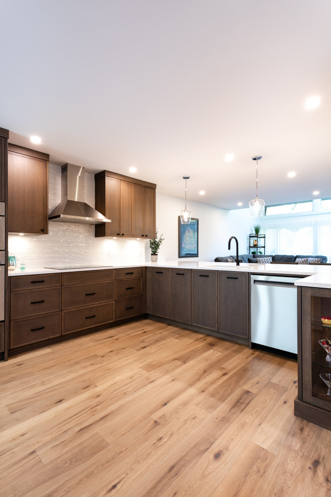 Open concept kitchen - mid-sized transitional u-shaped medium tone wood floor and brown floor open concept kitchen idea in Vancouver with an undermount sink, shaker cabinets, dark wood cabinets, quartz countertops, white backsplash, porcelain backsplash, stainless steel appliances, a peninsula and white countertops