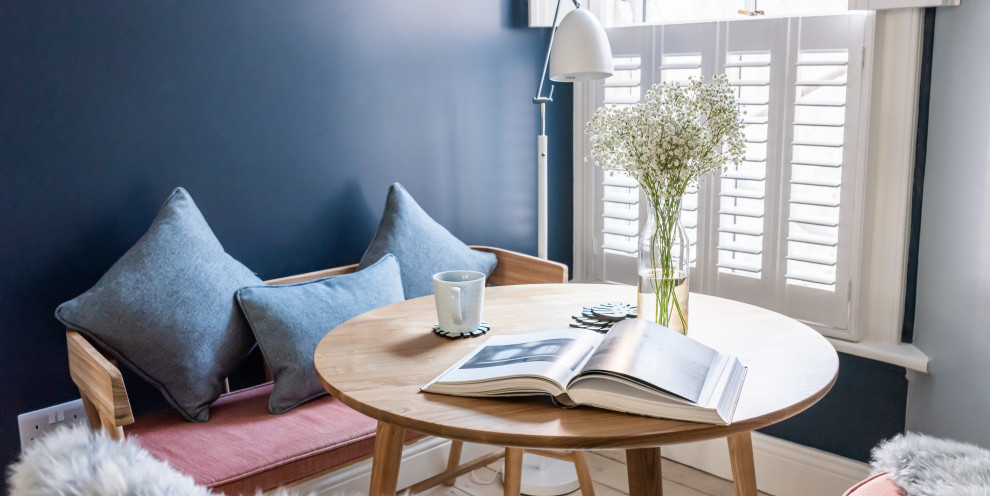 Kleines, Offenes Skandinavisches Wohnzimmer mit blauer Wandfarbe, hellem Holzboden, Kamin, Kaminumrandung aus Metall, freistehendem TV und freigelegten Dachbalken in Cornwall